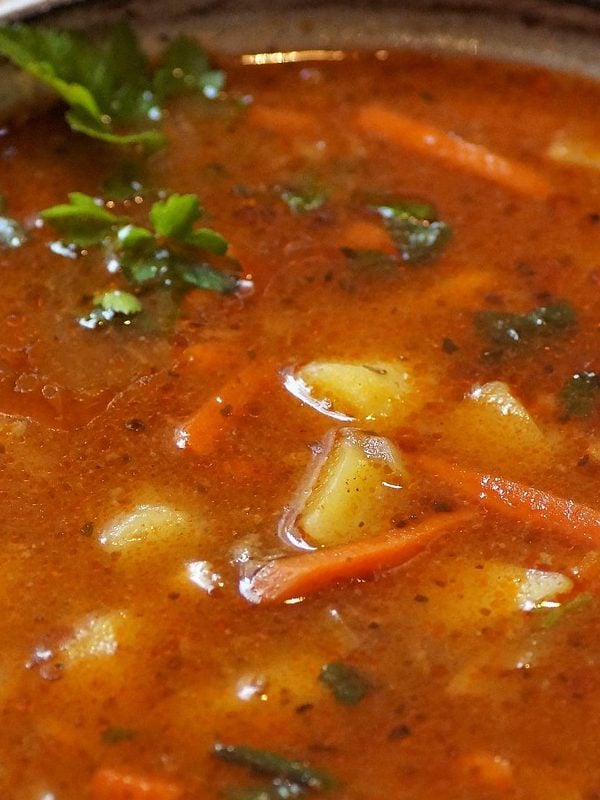 close up of goulash soup with bread and spoon