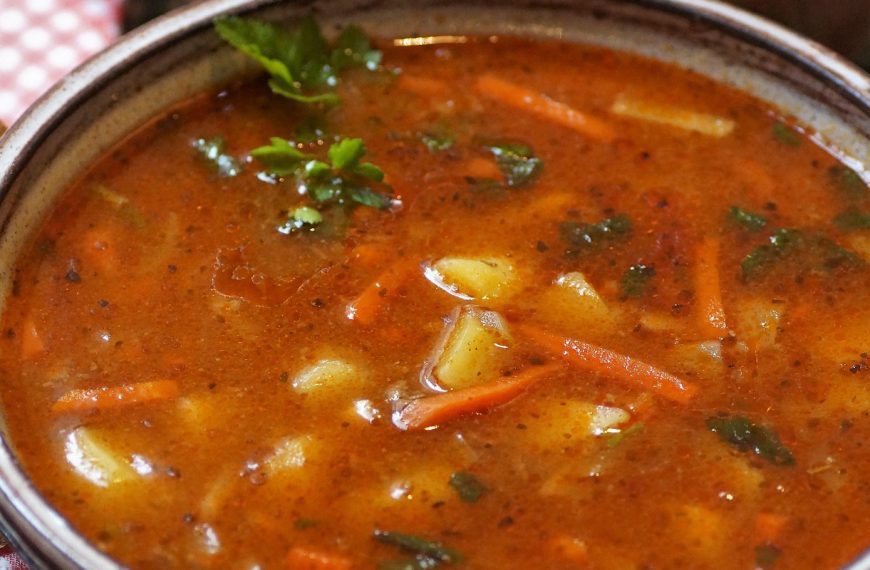 close up of goulash soup with bread and spoon