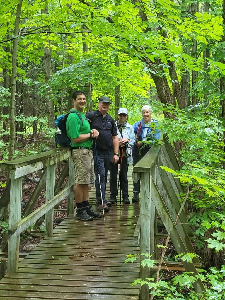 Our club's newest hike leader Alan stops at a bridge for a picture with hikers during a wet first hike